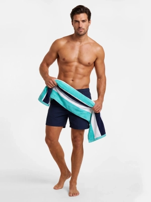 Turkusowo-biały ręcznik plażowy Sunny Day RK/844 przewiązany na biodrach modela.