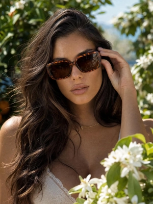 Brązowe okulary przeciwsłoneczne Salma na modelce w plenerze wśród zieleni.